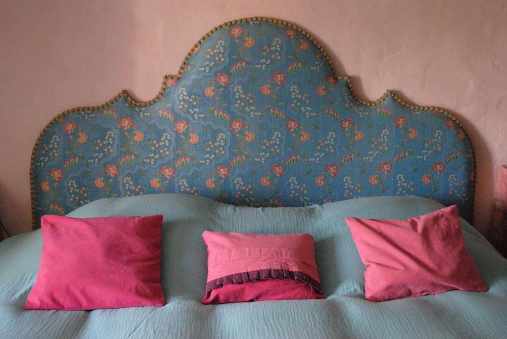 a bed with a blue headboard and pink pillows at Le Ragois in Richelieu