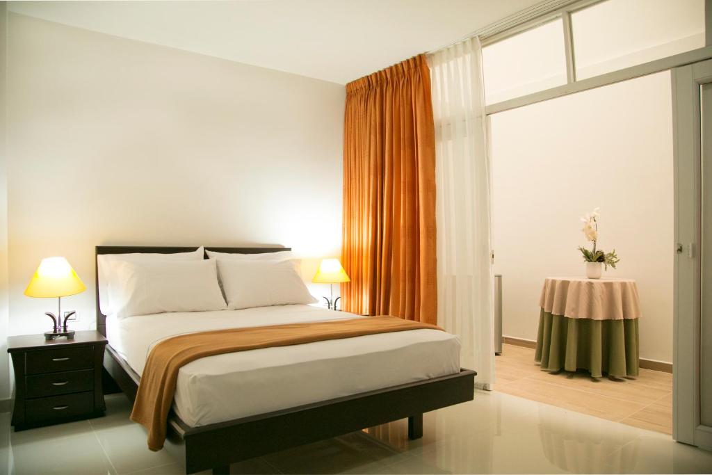 a bedroom with a bed and a window and a table at Hotel Casimena in Yopal