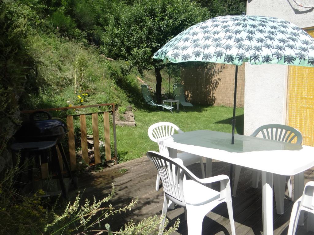 a table and chairs with an umbrella in a yard at Gite Le Maty in Saint-André-Capcèze