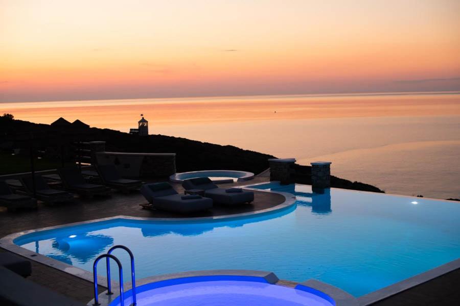 a large swimming pool with a sunset in the background at Toxotis Villas in Armenistis