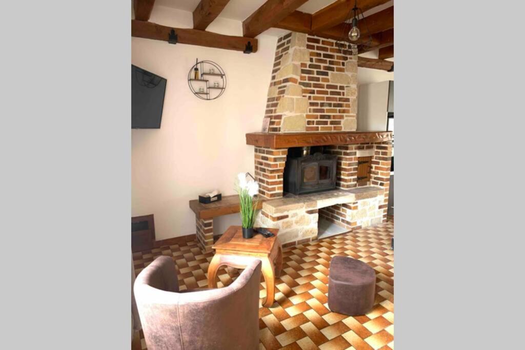 sala de estar con chimenea de piedra y sillas en Maison solognote proche Chambord, en Saint Laurent Nouan