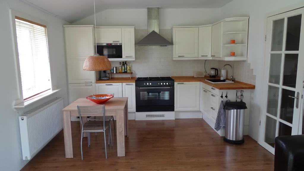 uma cozinha com armários brancos, uma mesa e um fogão em Apartment ARDA em Spijk