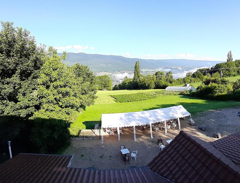 ein Zelt und Stühle in einem Hof mit einem Feld in der Unterkunft GITE AUBERGE EDELWEISS in Seyssel