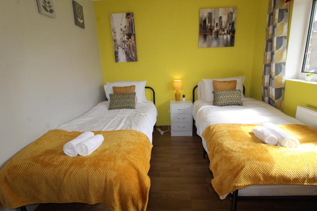 two beds in a room with yellow walls at Raynald House in Sheffield