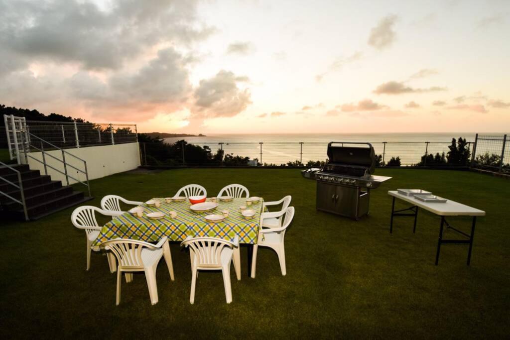 NakadomariにあるSEAVIEW VILLAS&HOUSE ONNAのテーブルと椅子、グリルと海