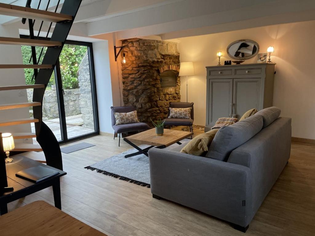 Tardinghen的住宿－les gites du grand saule，客厅设有灰色的沙发和石墙