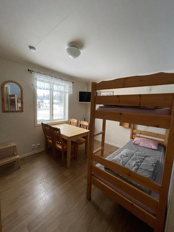 a room with a table and a bunk bed at Turistgården Töcksfors in Töcksfors