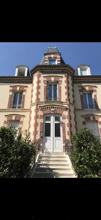 - un grand bâtiment en briques avec une porte blanche et des escaliers dans l'établissement Villa saint Louis 4, à Cabourg