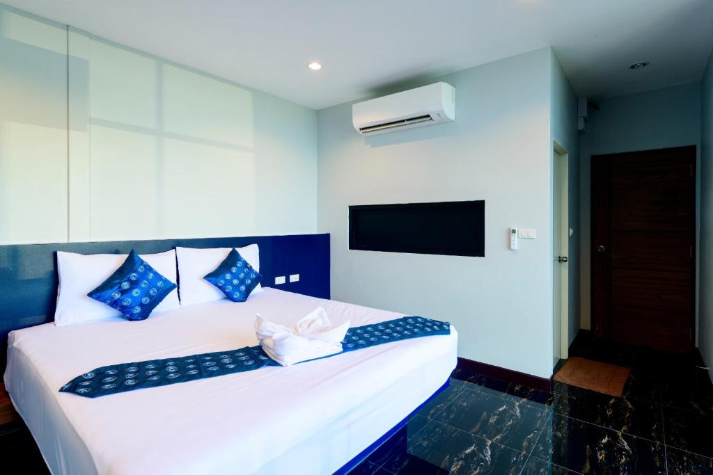 a bedroom with a large white bed with blue pillows at Skyline Resort in Ban Khlong Lat Bua Khao