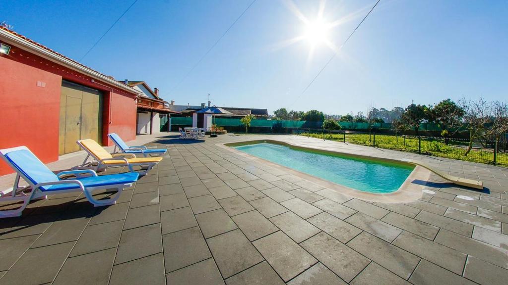 una piscina con sedie a sdraio accanto a una casa di 5 bedrooms villa with private pool enclosed garden and wifi at Catanhede a Cantanhede