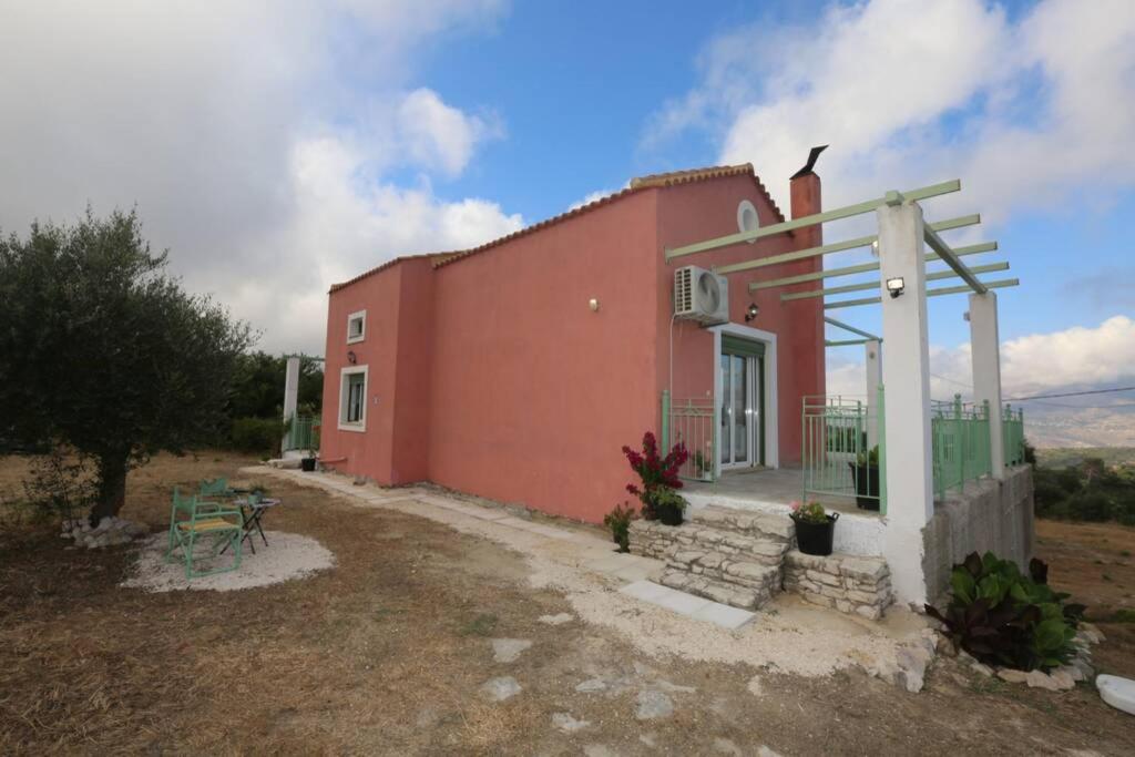 a small red house with a picnic table in front of it at Kalamakia House-stylish cottage near Petani beach in Lixouri