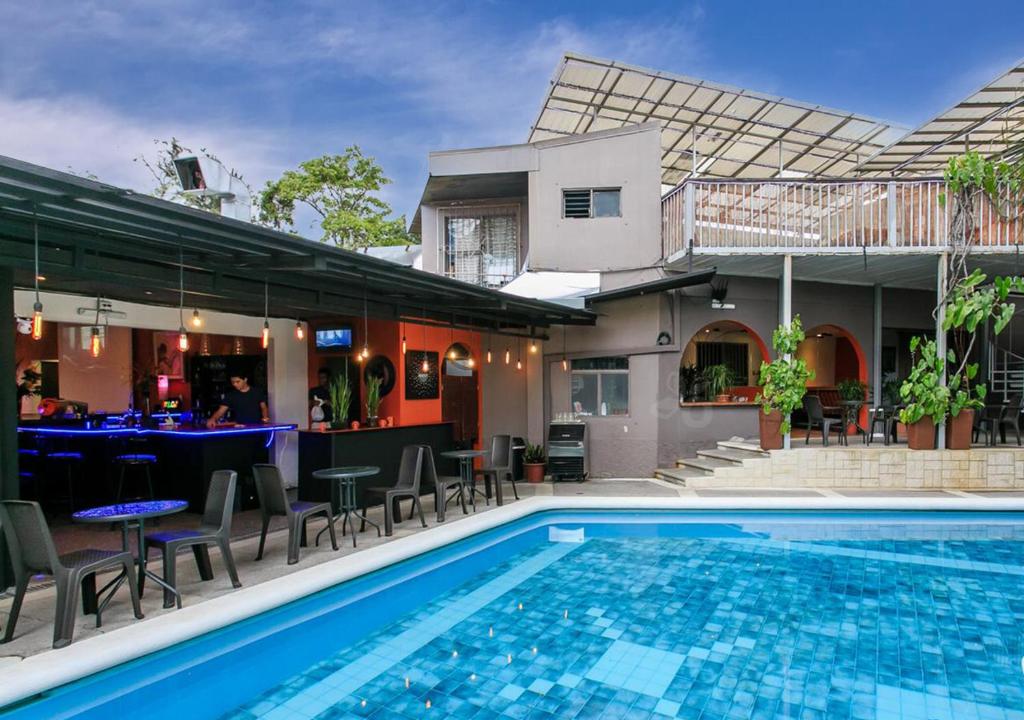 una piscina con sillas, un bar y una casa en Colours LGBTIQ Boutique Hotel & Hostal Coliving, en San José