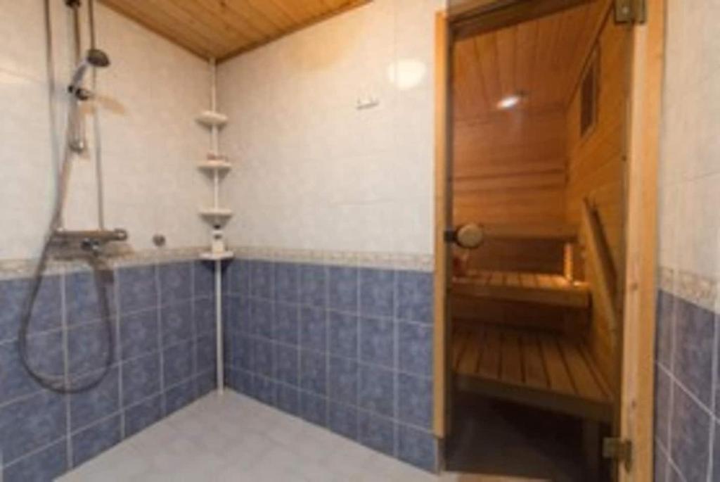 a bathroom with a shower and a blue tiled wall at Homestay cozy hosting in Tervakoski
