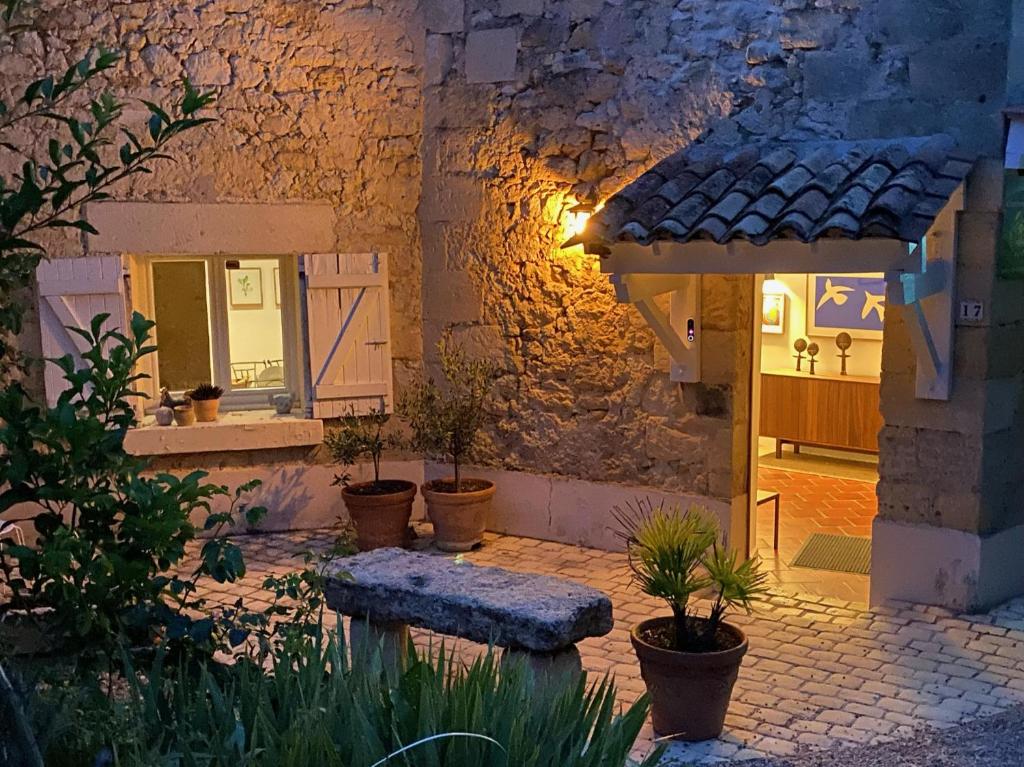 a courtyard of a house with a bench and potted plants at Le Prieuré de Saint Pierre in Saint-Pey-de-Castets