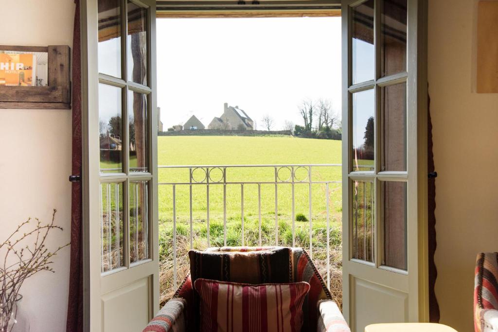an open door with a couch looking out at a field at The Annexe in Chipping Campden