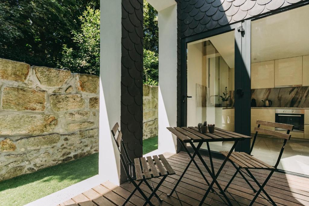 d'une terrasse avec une table et des chaises ainsi qu'un mur en pierre. dans l'établissement Aparthotel Oporto Palace, à Porto