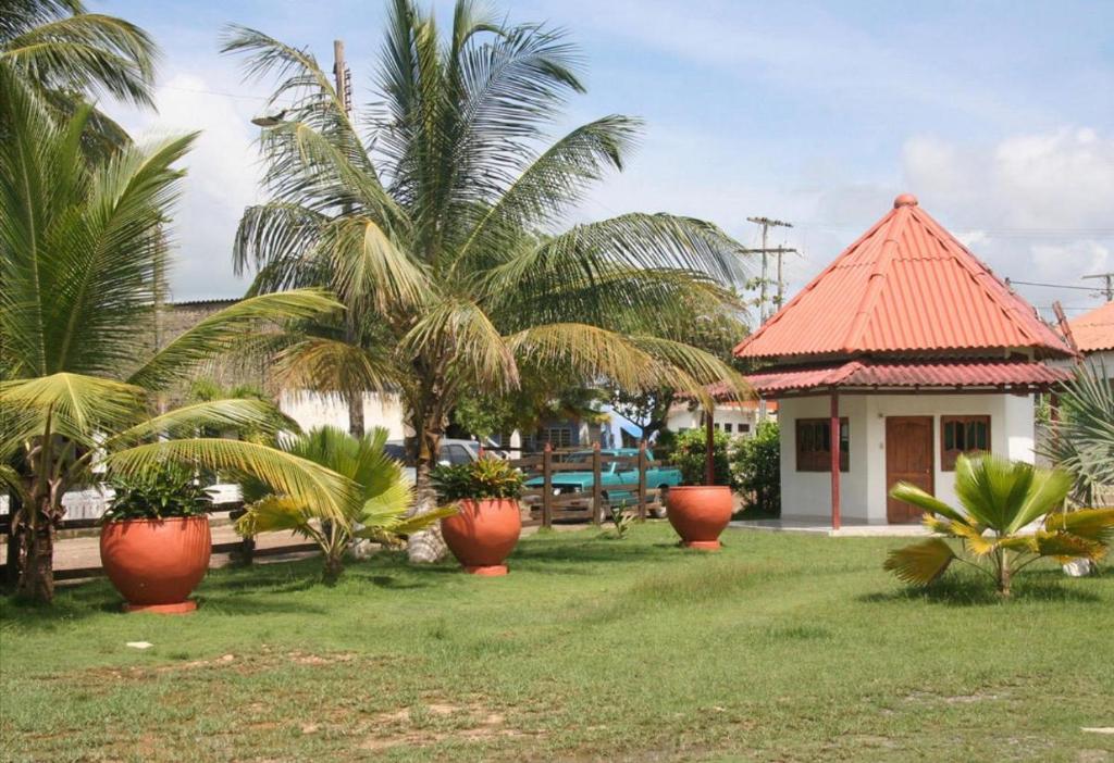 a yard with palm trees and a building with a house at Cabañitas del Mar by Rotamundos in Coveñas