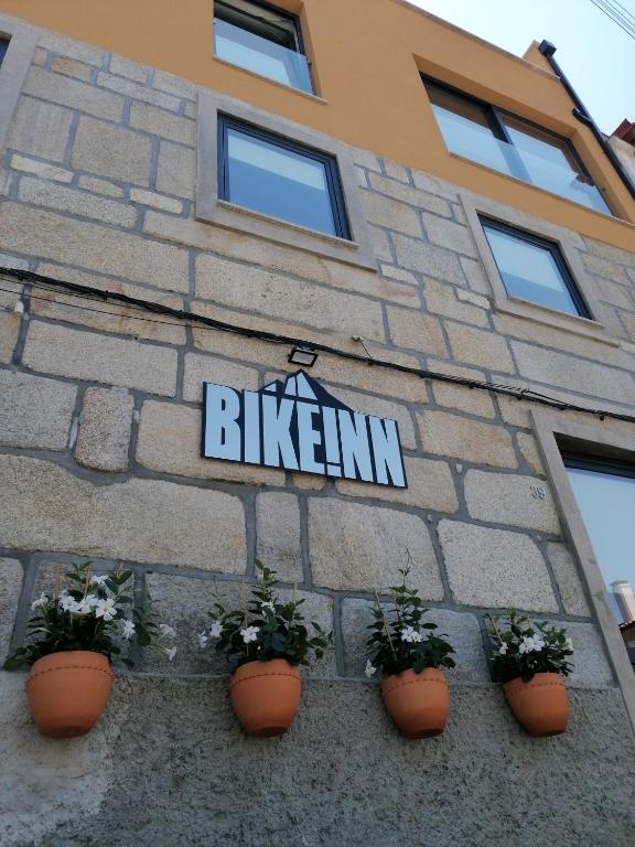 a sign on the side of a building with plants at BIKEINN in Vouzela