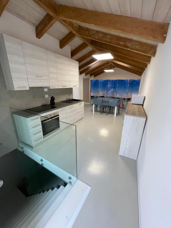 a large kitchen with white cabinets and a table at Loft Regina Margherita in SantʼAntìoco