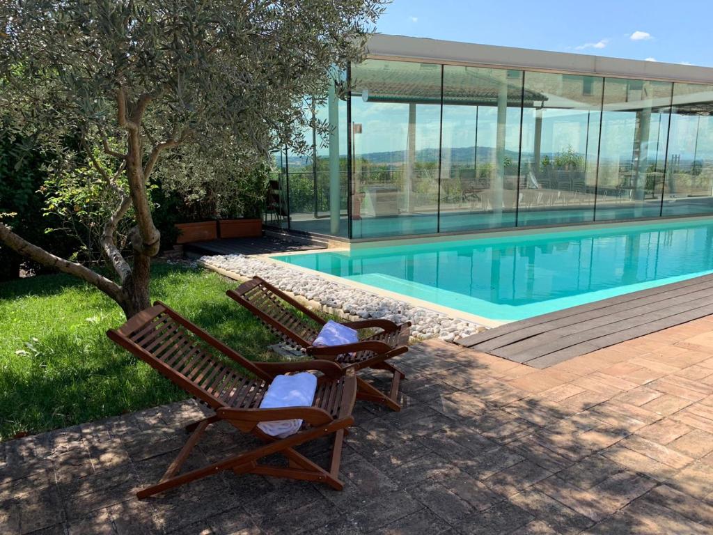 - deux chaises assises à côté de la piscine dans l'établissement Corte Fratini Appartamenti, à Trevi