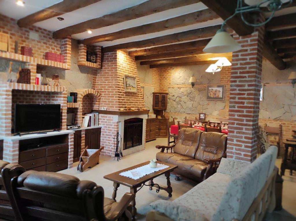 Casa Rural Puerta de Castilla في Velayos: غرفة معيشة مع أريكة ومدفأة
