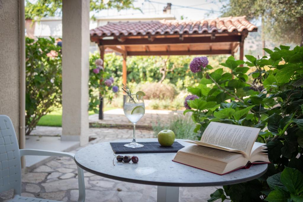 a table with a book and an apple and a glass of wine at Syvota Gardens in Syvota