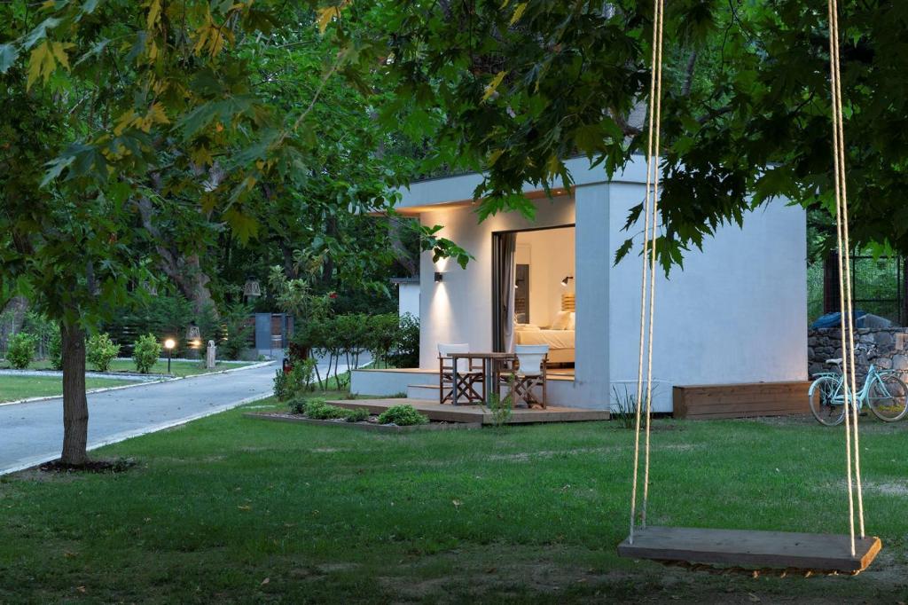 una pequeña casa blanca con un columpio en un patio en Gkaras Campsite & Apartments, en Leptokarya