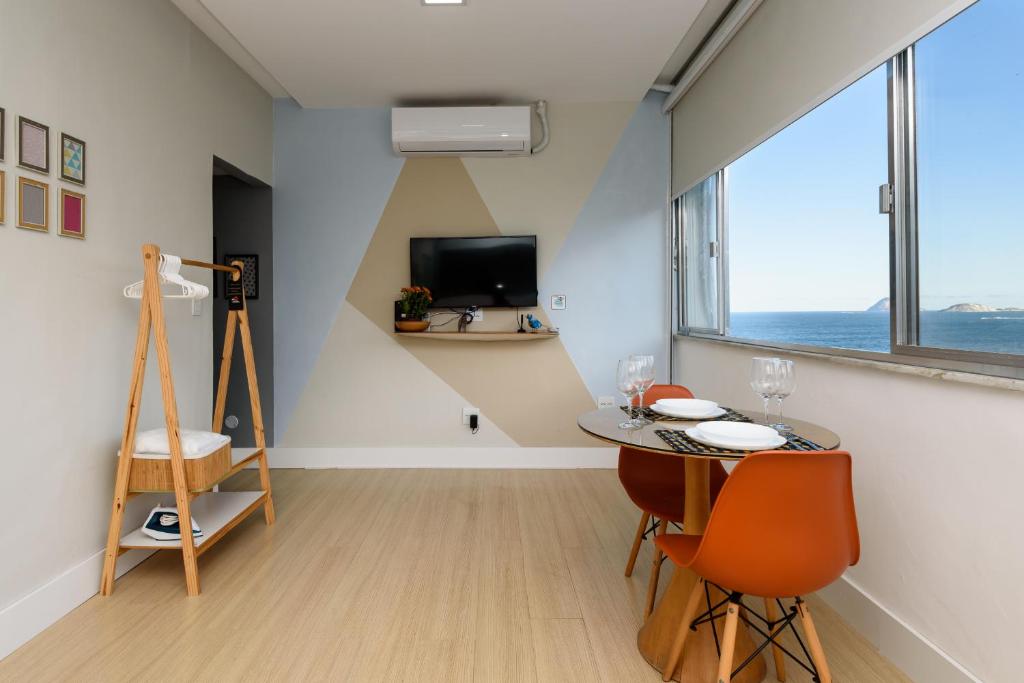 Zimmer mit einem Tisch, Stühlen und einem TV in der Unterkunft Vista da praia de Copacabana - NSC1006 Z3 in Rio de Janeiro