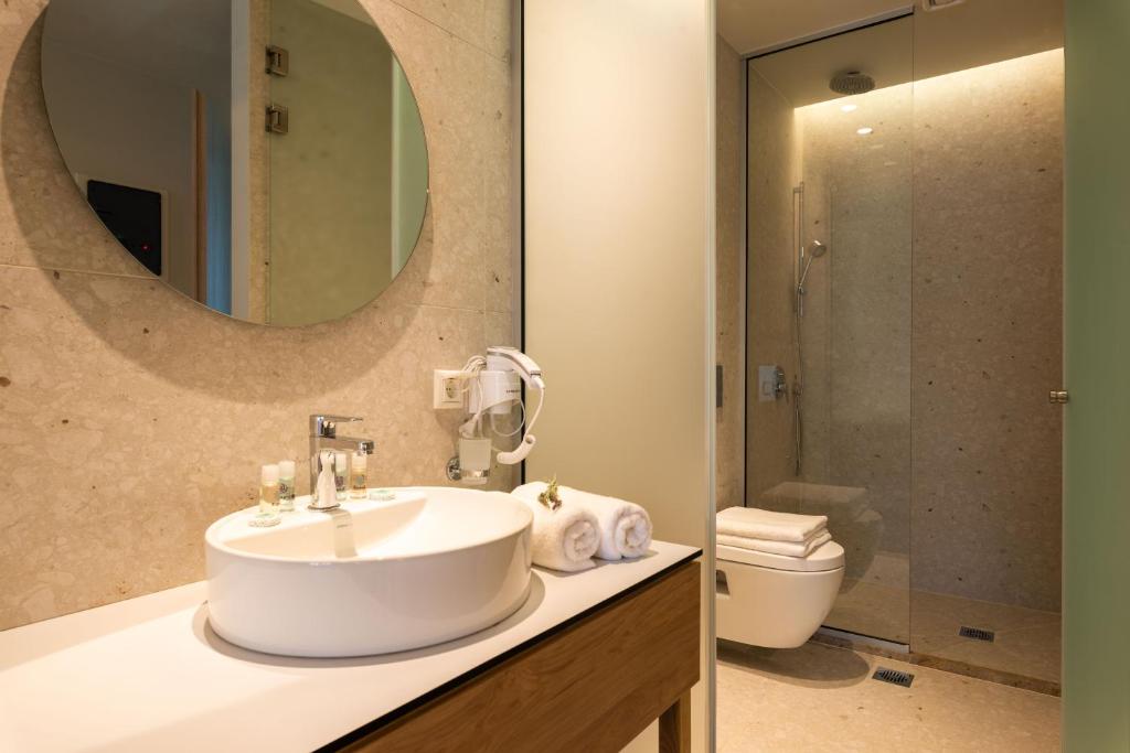 a bathroom with a sink and a toilet and a mirror at Syvota Gardens in Syvota