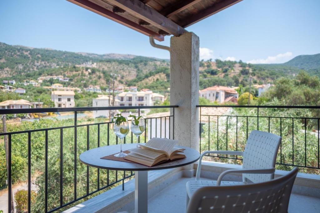 a table with a book and two chairs on a balcony at Syvota Gardens in Syvota