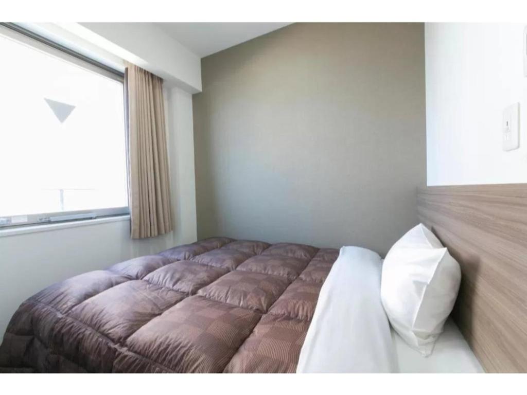 a bedroom with a bed with a large window at R&B Hotel Shin Osaka Kitaguchi - Vacation STAY 40553v in Osaka