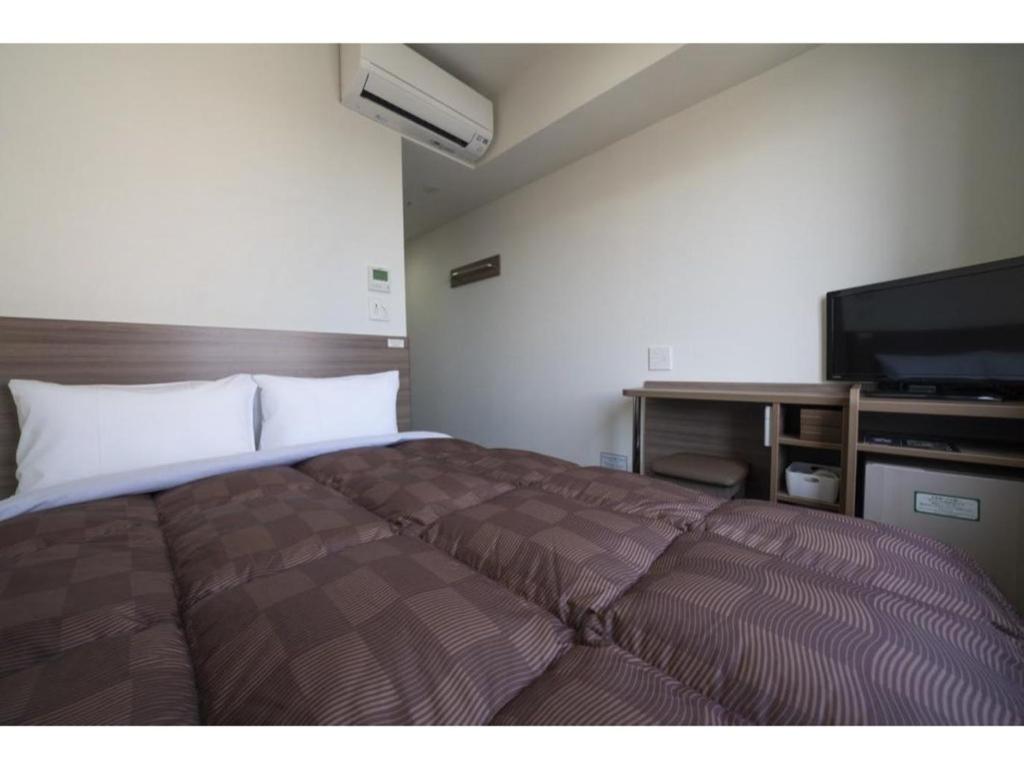een slaapkamer met een bed en een flatscreen-tv bij R&B Hotel Hakata Ekimae 2 - Vacation STAY 40725v in Fukuoka