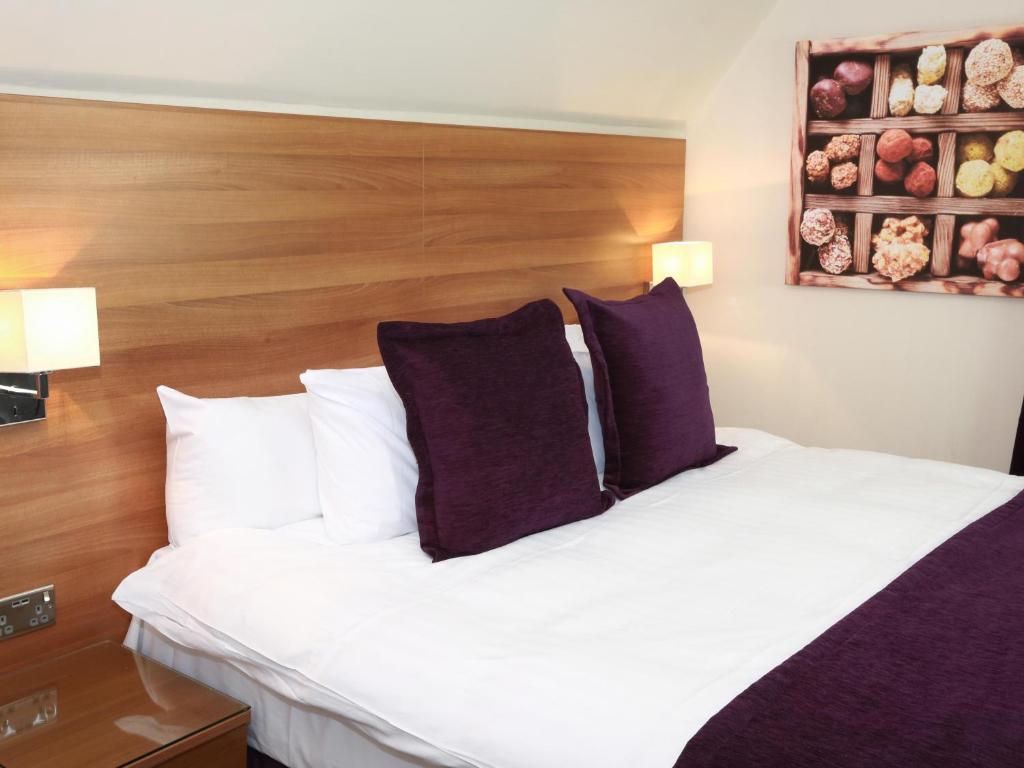 a bedroom with a large white bed with purple pillows at The Chocolate Box Hotel in Bournemouth