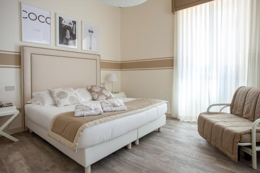 Hotel Olimpia في فورتي دي مارمي: غرفة نوم بسرير ابيض كبير وكرسي
