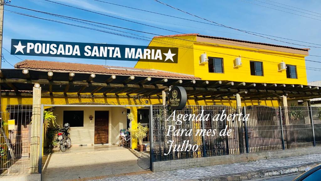 un bâtiment jaune avec un panneau en haut dans l'établissement Pousada Santa Maria, à Aparecida