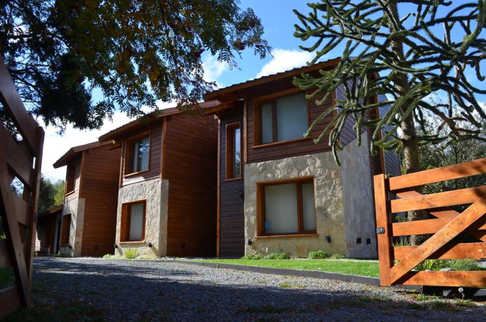 a house with a wooden fence in front of it at La Araucaria in Villa La Angostura