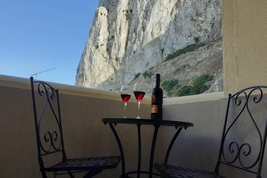 two glasses of wine on a table with two chairs at Bright and central 2 bedroom flat in Gibraltar in Gibraltar