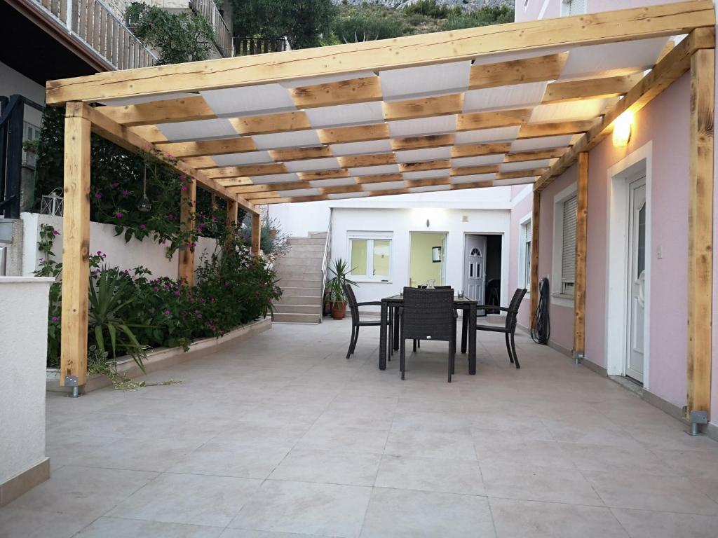 a patio with a table and chairs under a wooden pergola at Apartmani Maki in Omiš