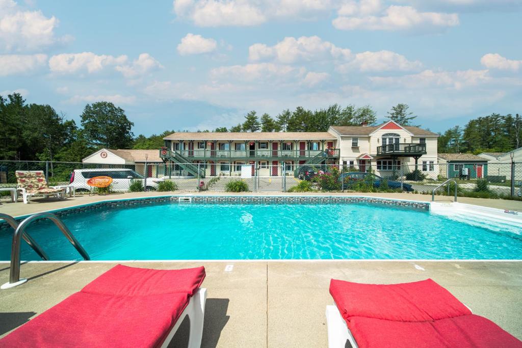 a swimming pool with two lounge chairs in front of a building at Wagon Wheel Motel in Saco