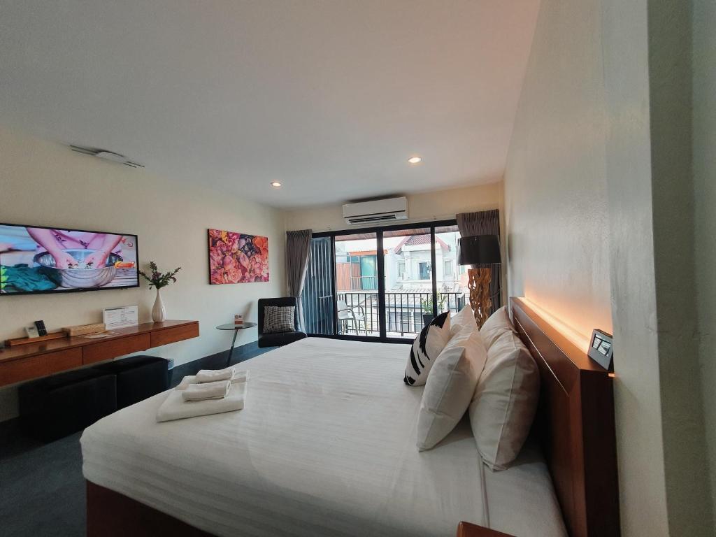 - une chambre avec un grand lit blanc et une fenêtre dans l'établissement The Sila Boutique Bed & Breakfast, à Chiang Mai