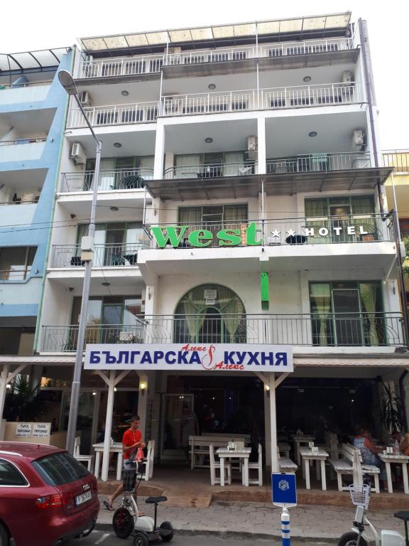 a tall white building with a sign on it at Къща за гости WEST in Sunny Beach