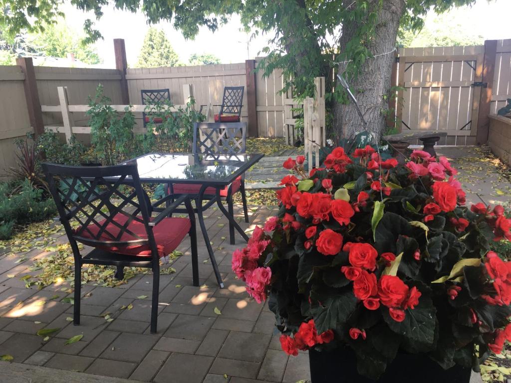 a patio with a table and a bunch of red flowers at K STREET CARRIAGE HOUSE Studio in Penticton