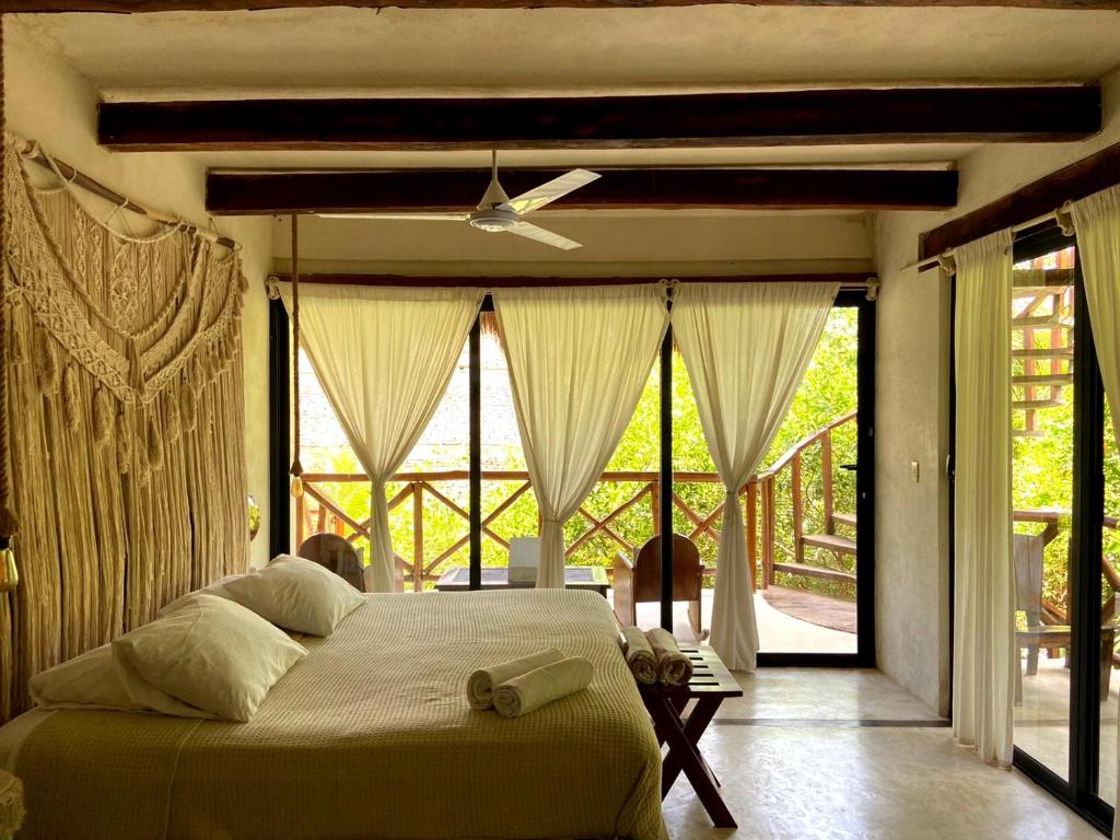 een slaapkamer met een groot bed en grote ramen bij La Casa de Mia Tulum in Tulum