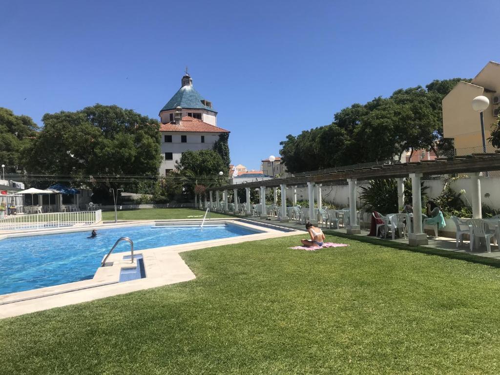 a person sitting on the grass next to a swimming pool at Porto Marina - Prime Residence in Vilamoura