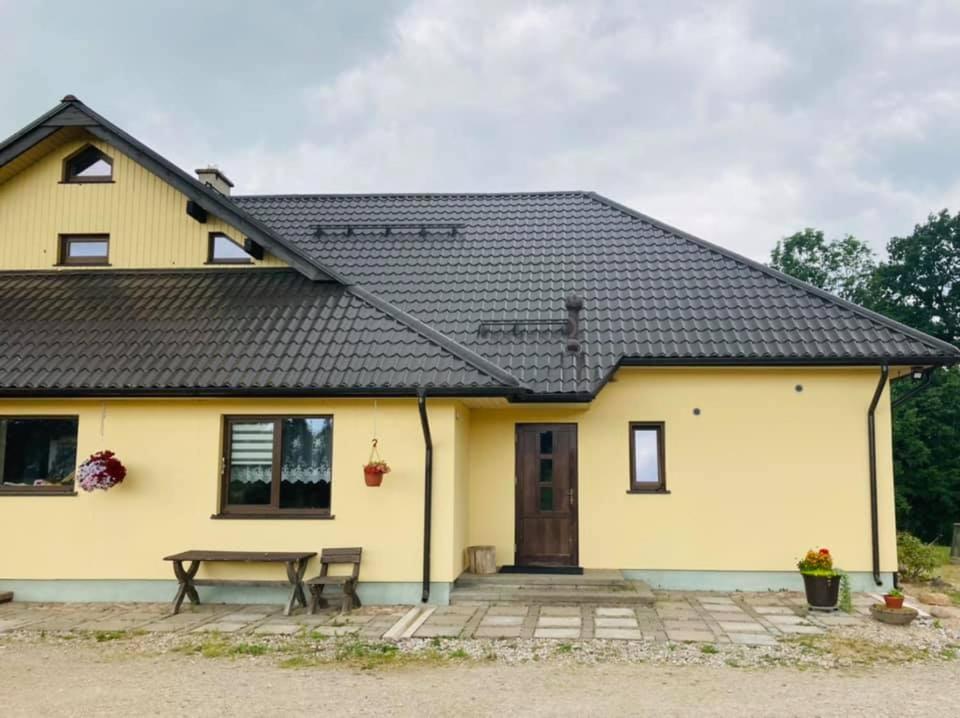 una casa amarilla con una mesa de picnic delante de ella en Svētgravas, en Aklaisciems