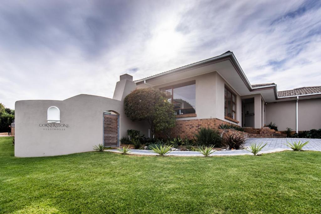 a white house with a grass yard at Cornerstone Guesthouse in Cape Town