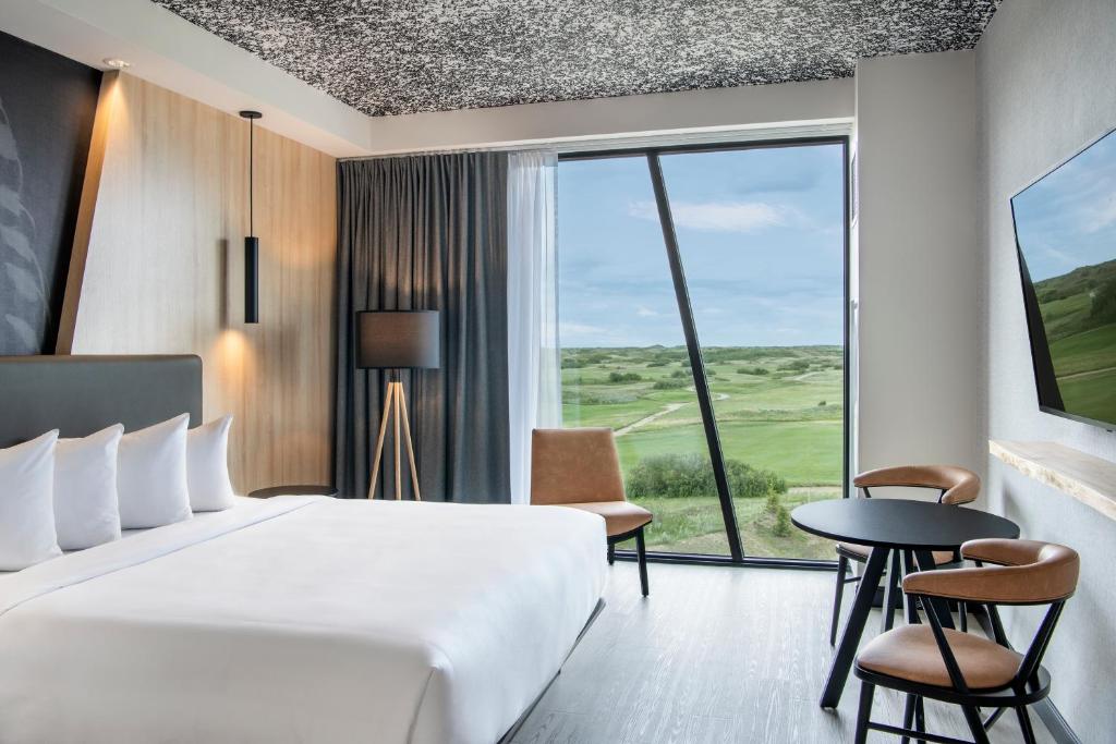 a hotel room with a bed and a table and a window at Dakota Dunes Resort in Dundurn