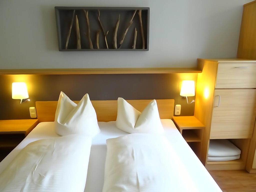 a hotel room with a bed with white pillows at "Blauer Bock" - Hotel-Garni in Pleinfeld