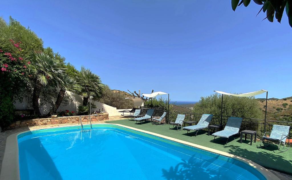 a swimming pool with chairs and a view of the ocean at Appartamento Mariposa in Budoni