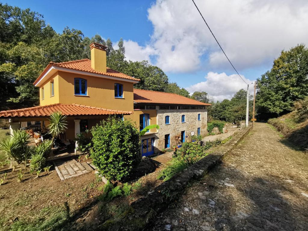 a yellow house on a hill next to a road at Quinta Estrada Romana - Albergue de Peregrinos in Cerdal